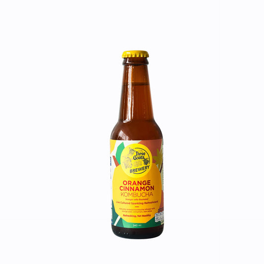A bottle of Three Goats Brewery Orange Cinnamon Kombucha with a yellow label and orange peel cap.