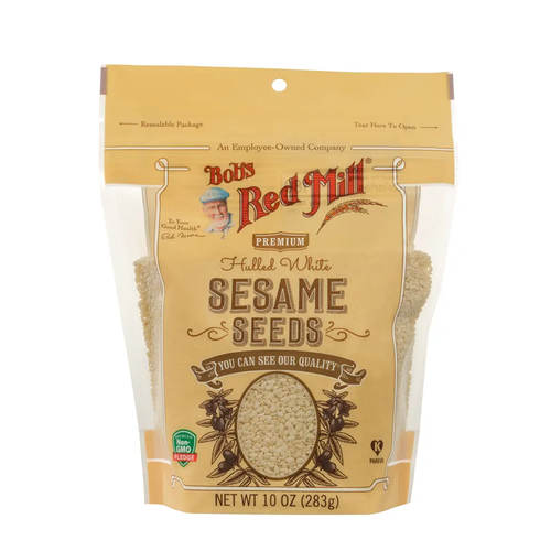 A 10 oz bag of Bob's Red Mill Premium Halled White Sesame Seeds, featuring a tan stand-up pouch with clear windows showing the light beige seeds inside.