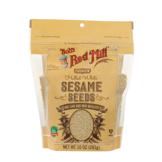 A 10 oz bag of Bob's Red Mill Premium Halled White Sesame Seeds, featuring a tan stand-up pouch with clear windows showing the light beige seeds inside.